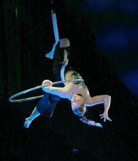 Frau w&auml;hrend Auftritts mit Luftring in aktobatischer Pose in der Luft mit atmosph&auml;rischem Licht