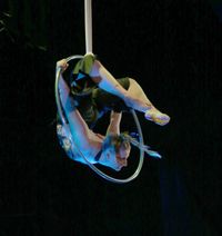 Frau w&auml;hrend Auftritts mit Luftring in aktobatischer Pose in der Luft mit atmosph&auml;rischem Licht